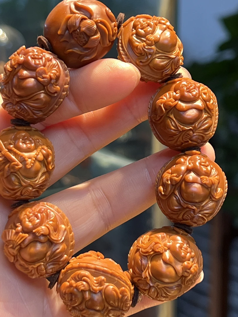 橄榄核雕刻浮雕弥勒，背面设计了荷叶荷花，弥勒神态法器各有不同