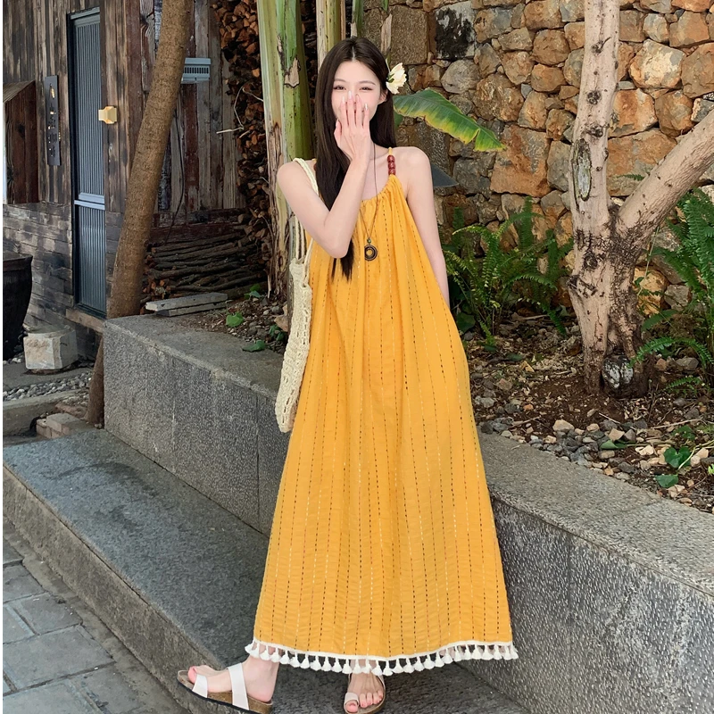 黄色流苏吊带连衣裙女夏2025新款宽松显瘦海边度假中长款休闲长裙